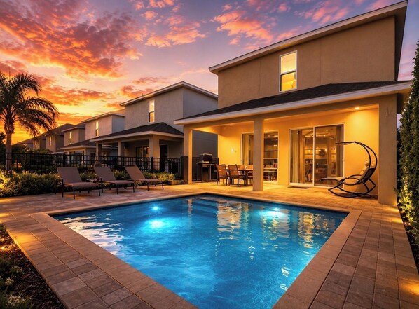 A residential property with a swimming pool, lounge chairs, and a patio area.