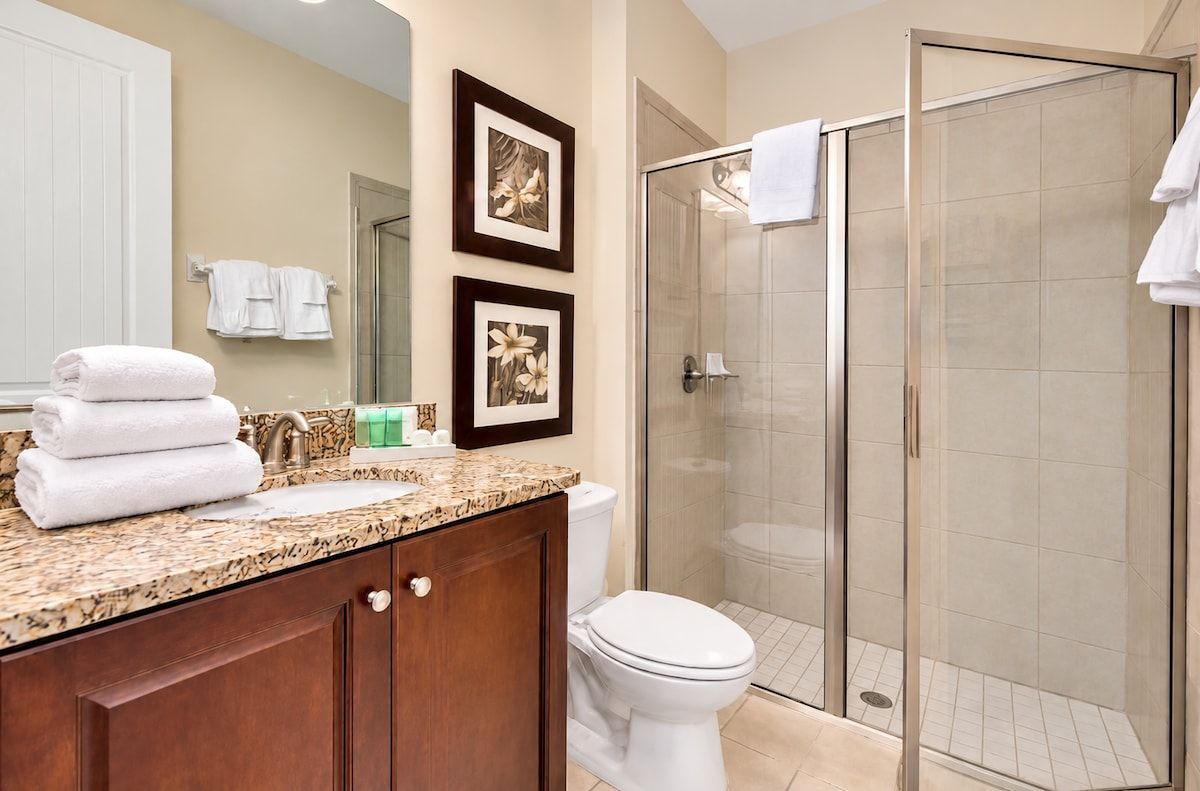 A bathroom with a sink, toilet, and glass shower enclosure.