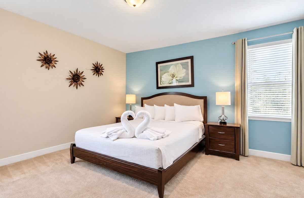 A bedroom with a bed, bedside lamps, a nightstand, and wall decor.