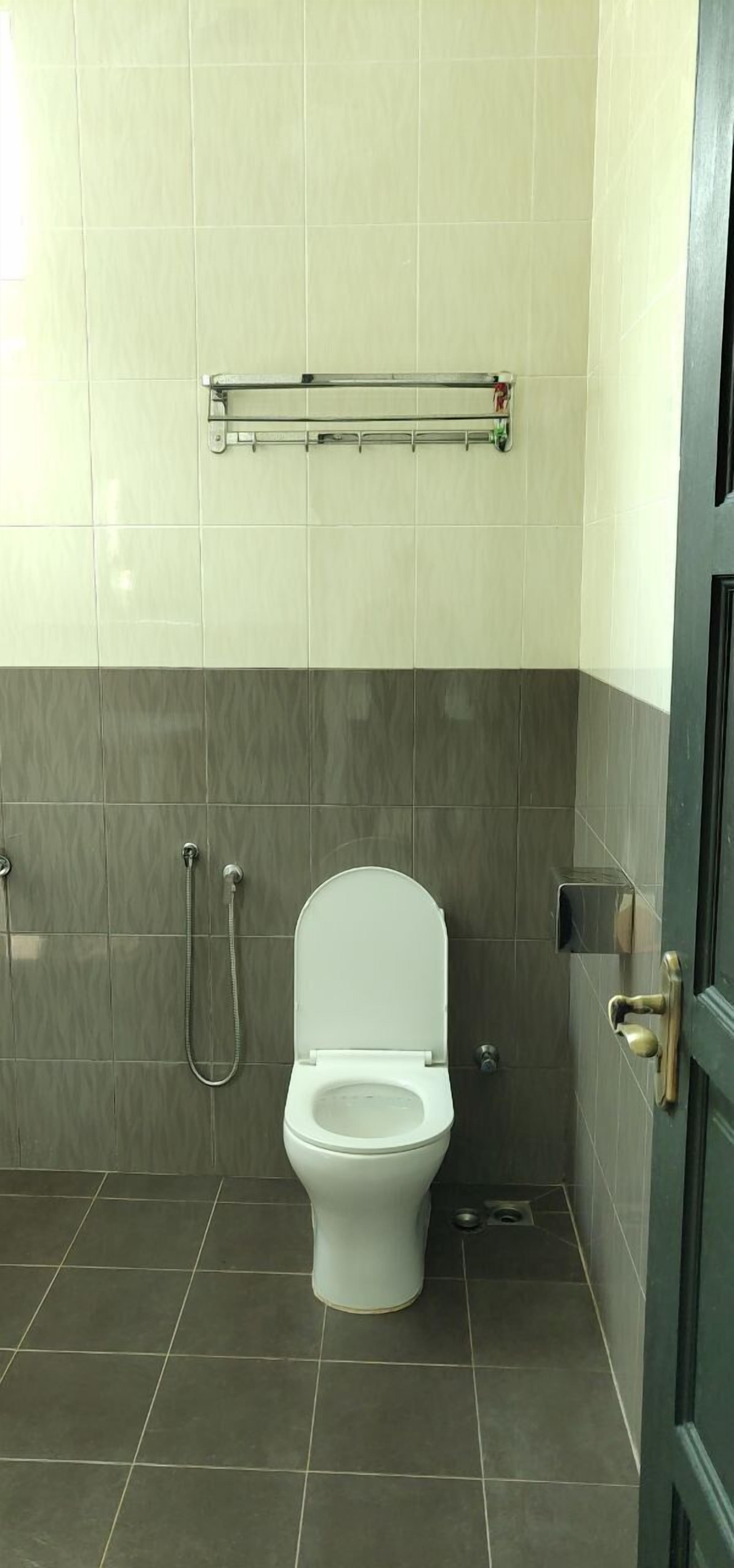 Un baño con inodoro, ducha y perchero para toallas.
