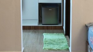 A compact kitchenette with wooden cabinets, a white countertop, and a small refrigerator. - Captain's Cabin Resort  (Kota Bharu)