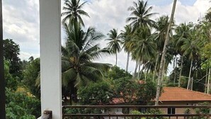 A covered balcony with a tiled floor, a metal railing, and a view of palm trees and a building in the background. - Captain's Cabin Resort  (Kota Bharu)