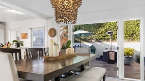 A spacious dining area with a long table, chairs, and a decorative hanging light fixture.