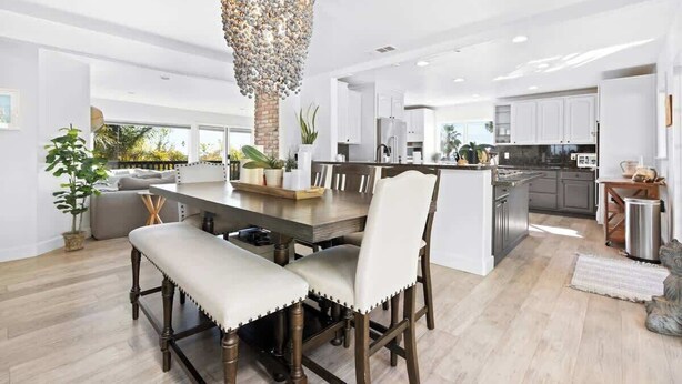 A modern kitchen with a central island, white cabinetry, and a chandelier.
