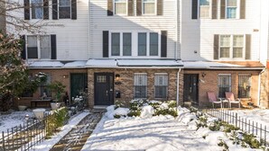 A row of townhouses with brick facades, white siding, and black shutters. - Central Convenient Home | Free Parking | Near U St (Washington)
