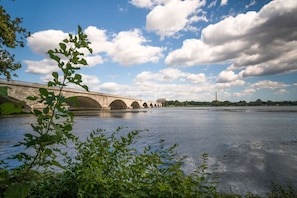 A stone bridge over a river with a clear sky and clouds.