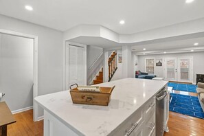 A spacious kitchen with a large island, a dining area, and a staircase leading to another level.