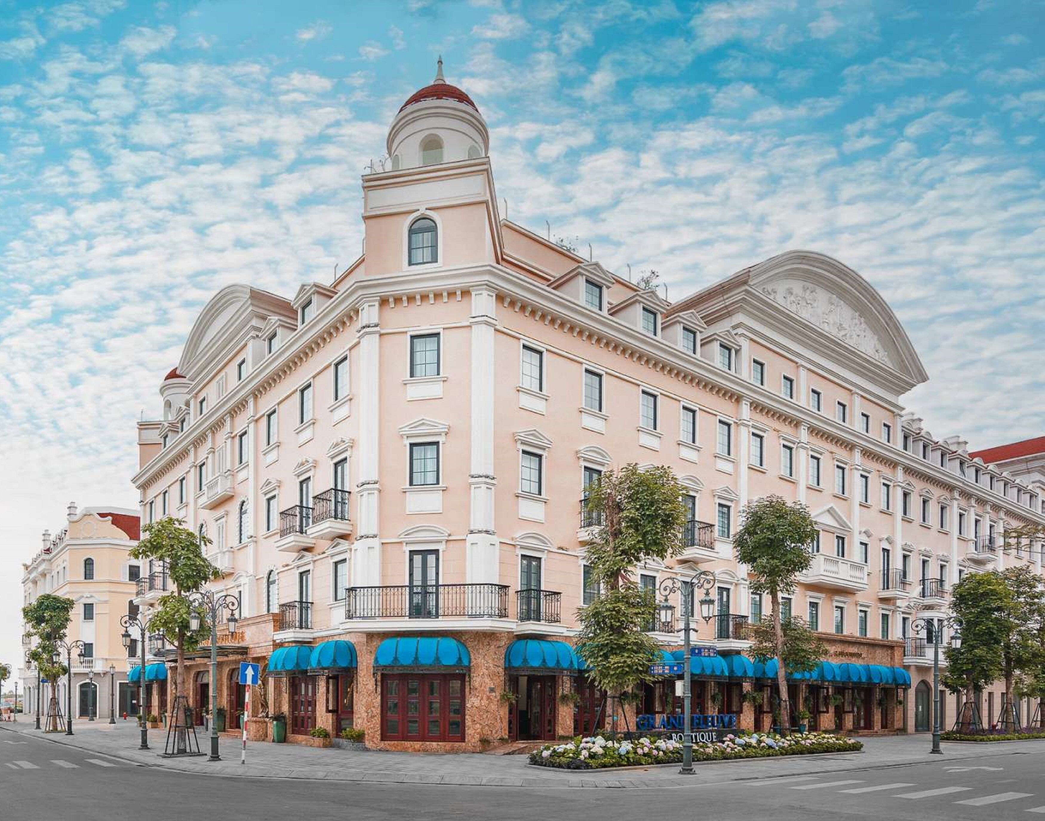 Un grand hôtel à plusieurs étages, de style architectural classique, avec un dôme central et des fenêtres disposées de manière symétrique.
