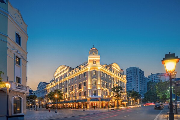 Un hotel histórico con una torre destacada, ventanas amplias y una fachada bien iluminada.
