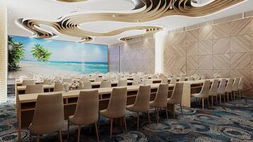 A conference room with a long table, chairs, a large screen, and a tropical beach mural.