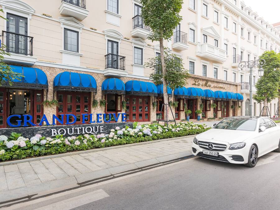 A building with a sign reading "GRANDELEUVE BOUTIQUE" and a white car parked in front.