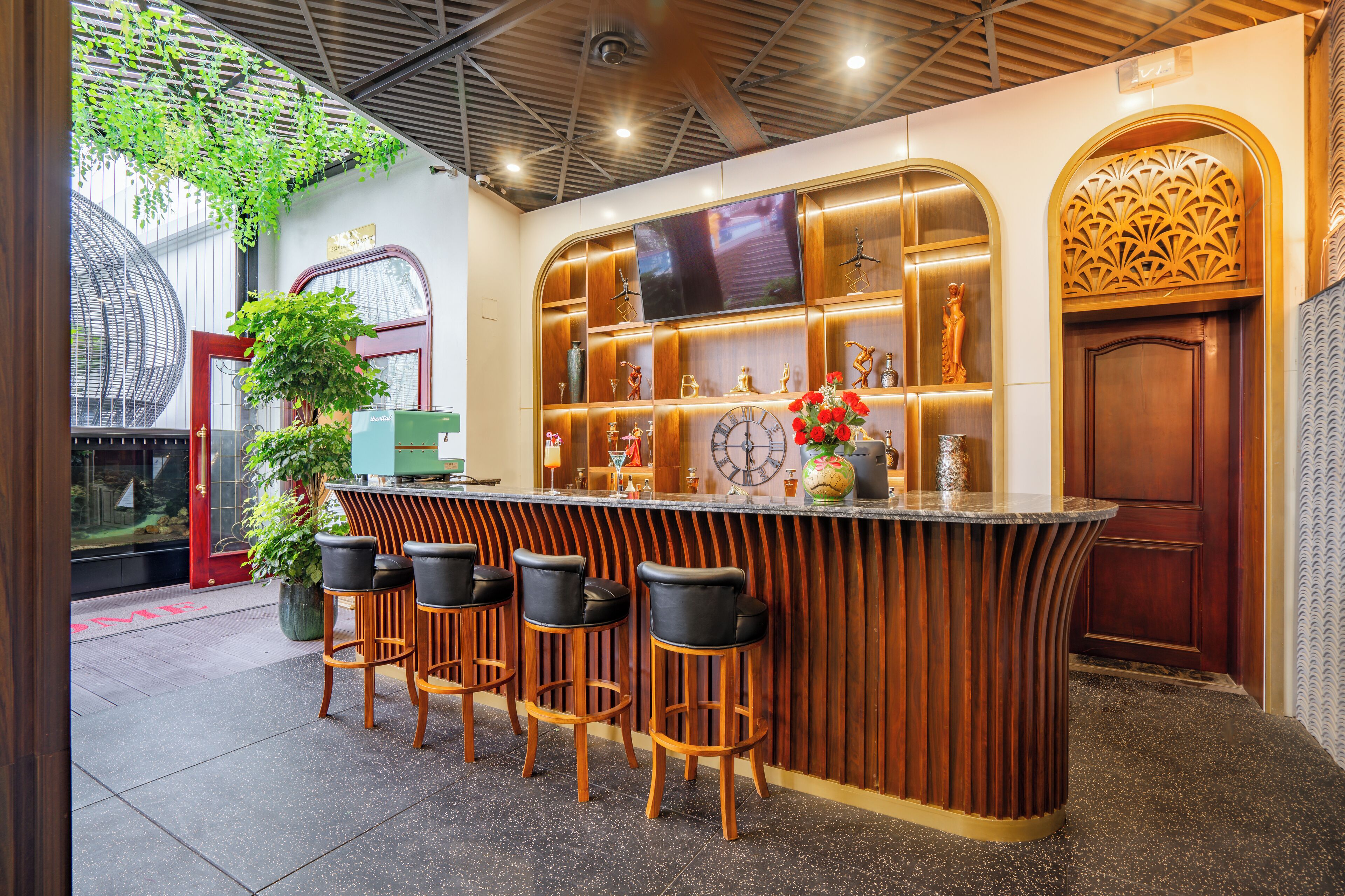A bar area with a curved wooden counter, bar stools, a large clock, and decorative items.
