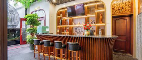 A bar area with a curved wooden counter, bar stools, a large clock, and decorative items.