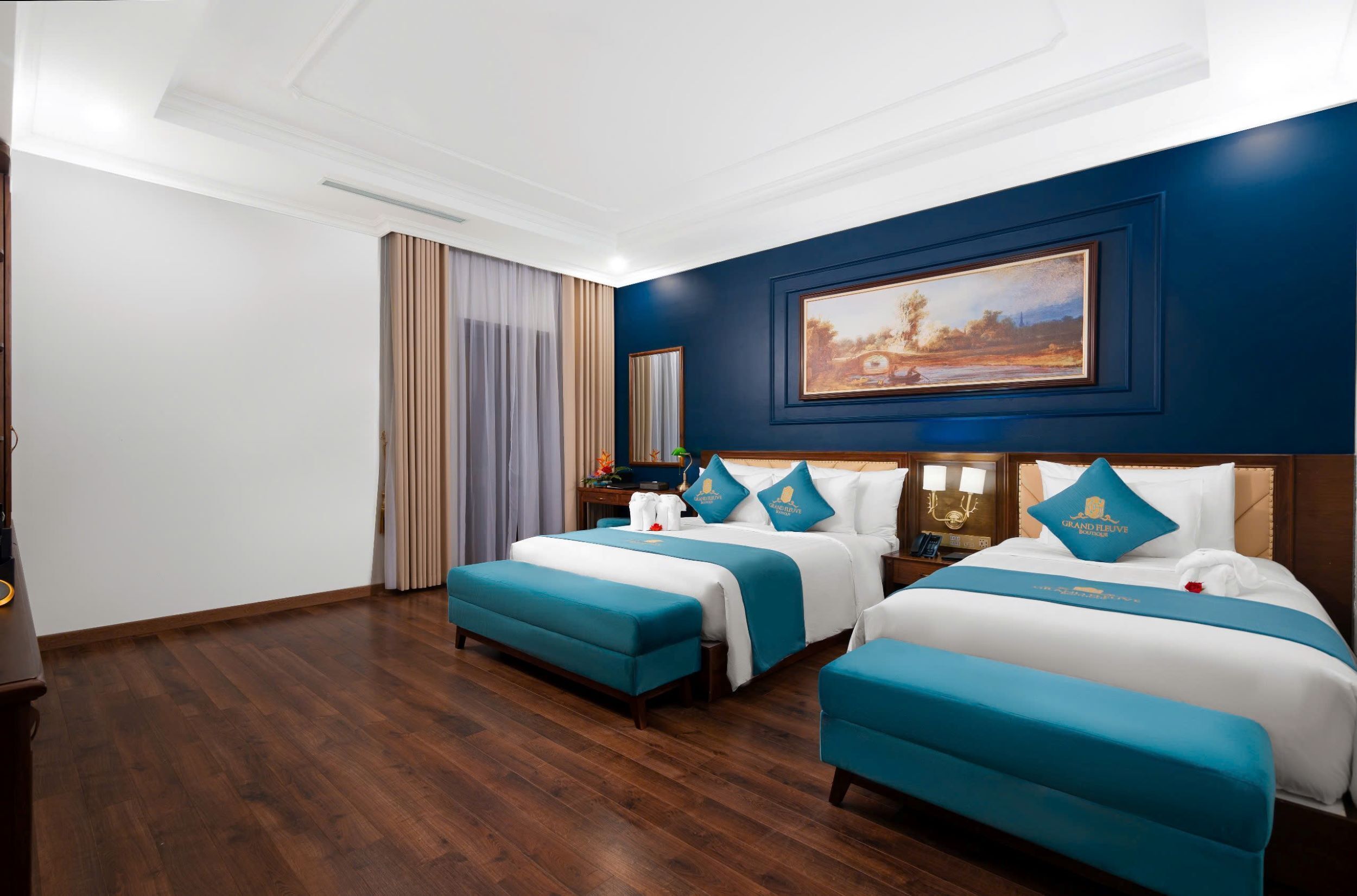 Une chambre d’hôtel avec deux lits, un grand tableau au mur et un plancher en bois.