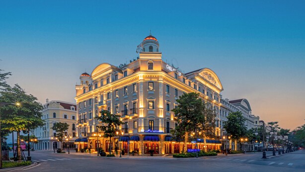 A grand hotel with a classical architectural style, featuring multiple stories, a prominent dome, and illuminated signage. - Grand Fleuve Boutique  (Bai Chay)