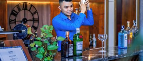 A bar area with a bartender preparing a drink, wooden decor, and a clock on the wall.