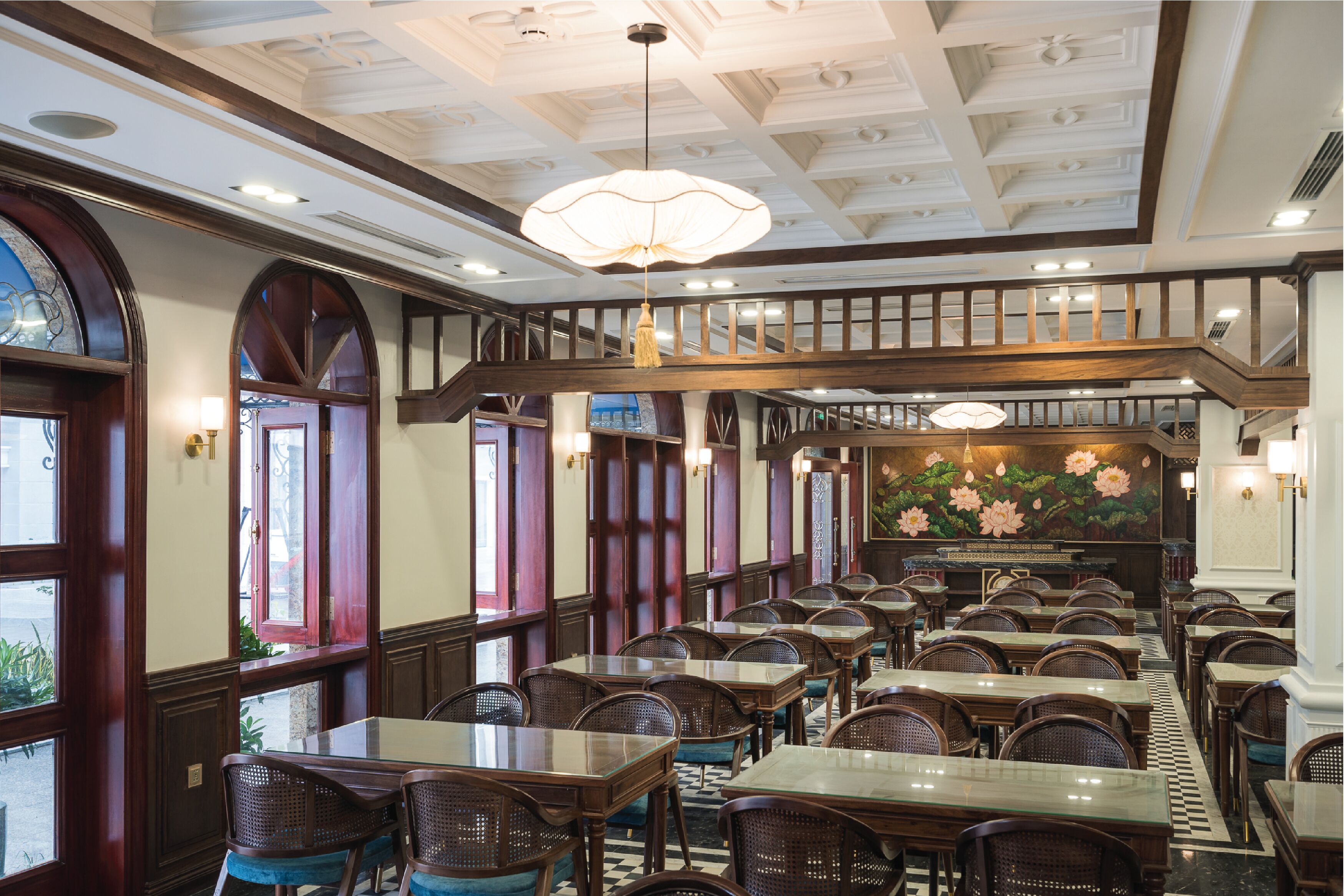 Un restaurant doté de nombreuses tables et chaises, de poutres en bois au plafond et d’une grande fresque murale au fond de la salle.