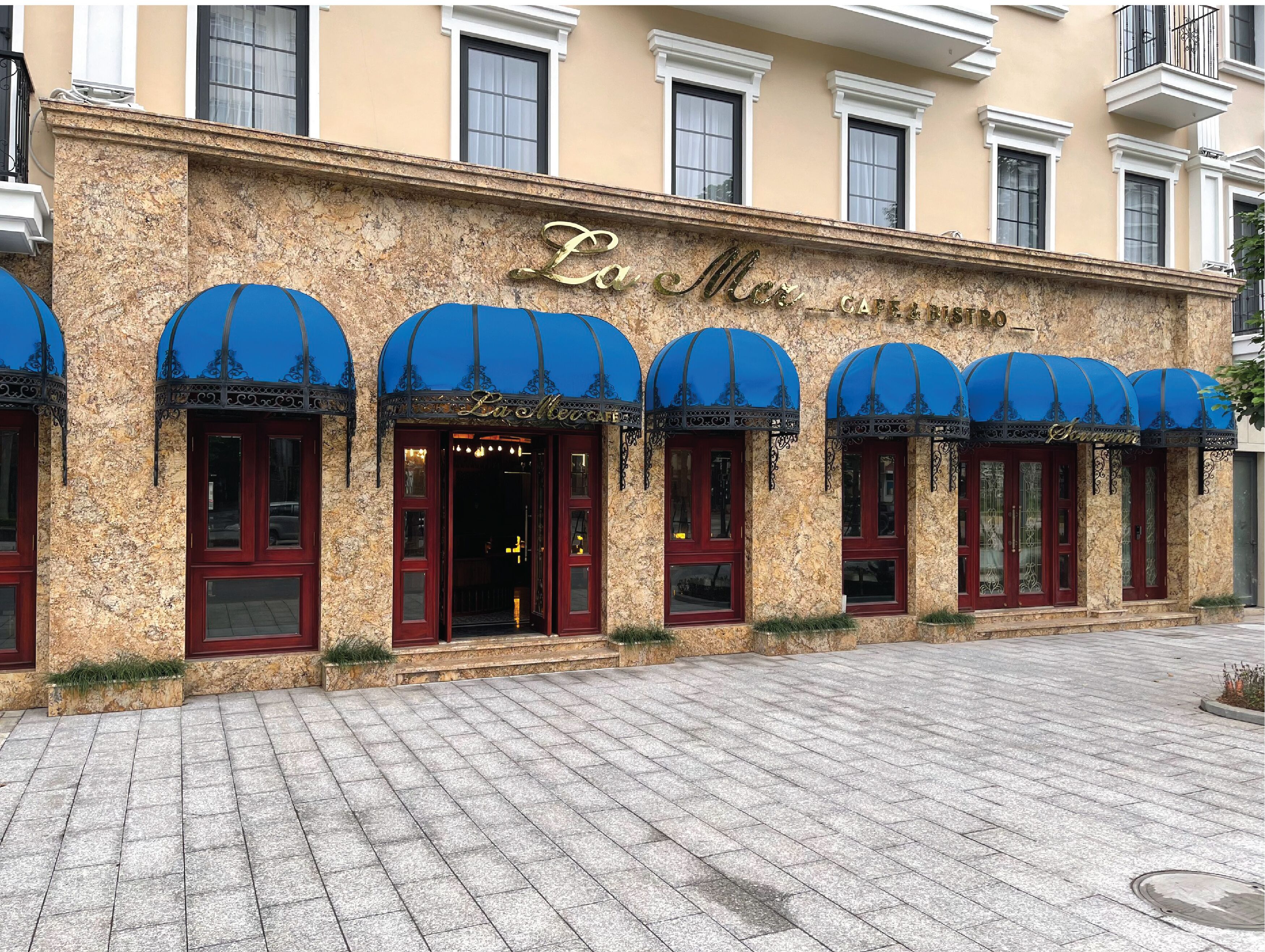 Fachada de un edificio con un letrero que dice 'La Maison Café & Bistro'.