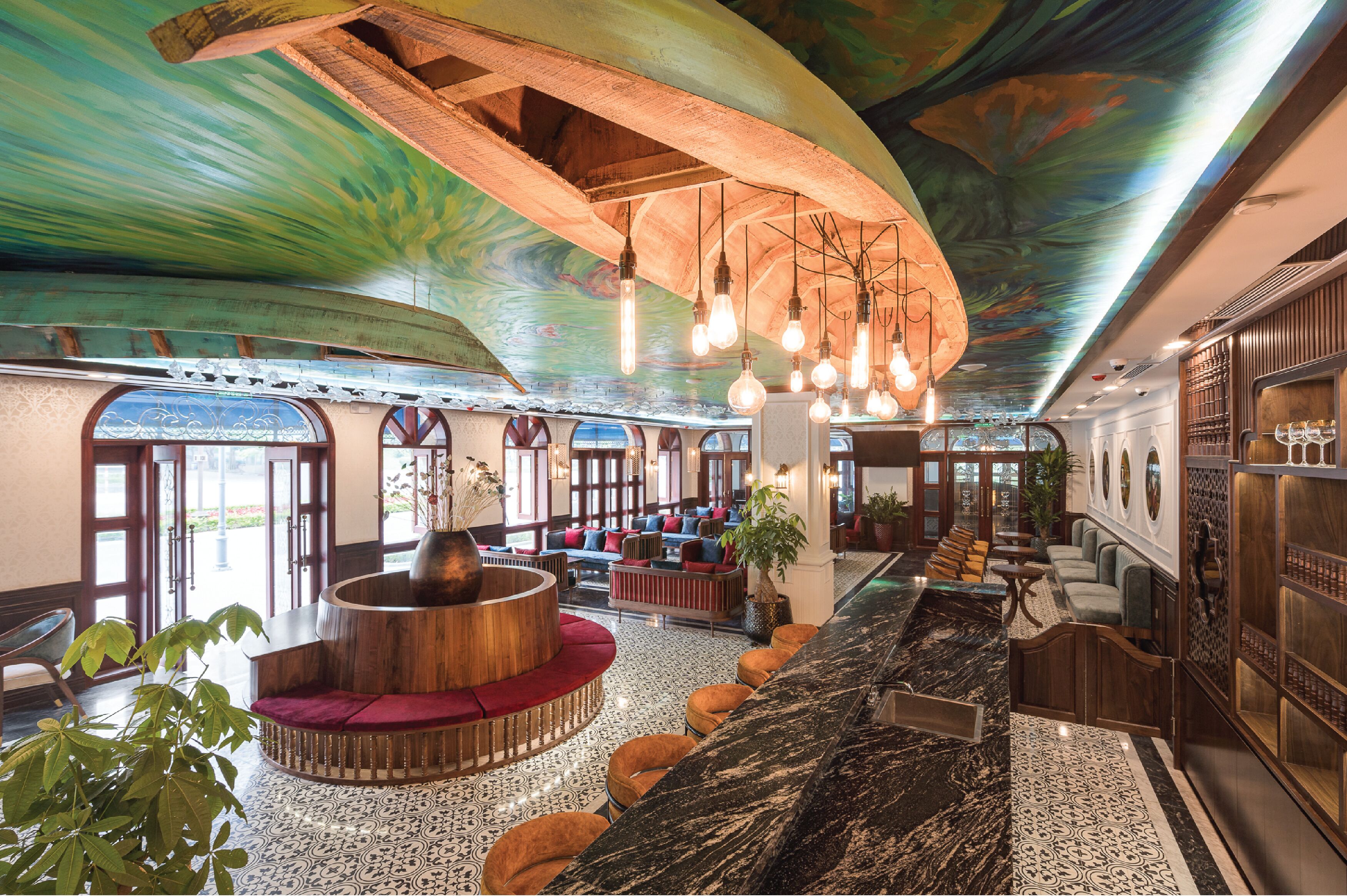 A spacious lobby with a curved wooden bench, seating area, and a marble reception desk.