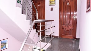 Eine Treppe mit Metallgeländern, die zu einer Zwischenebene führt, zwei Holztüren und eine Wand mit gerahmten Bildern.