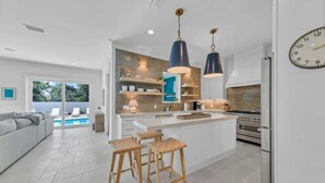 A modern kitchen with a central island, pendant lights, and a built-in oven. - Barton Vista Del Mar | Paradise Perfected!! | Deeded Access with Free Beach Chairs & Umbrellas 100 Yards Away! (Miramar Beach)