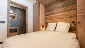Un dormitorio con cabecera de madera, cama con ropa de cama blanca, mesita de noche y espejo.