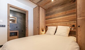 A bedroom with a wooden headboard, a bed with white bedding, a nightstand, and a mirror.