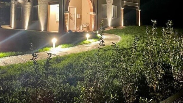 A two-story house with a large arched entrance, a balcony on the upper floor, and a well-lit driveway. - Casa Pralunghi b&b  (Calvene)