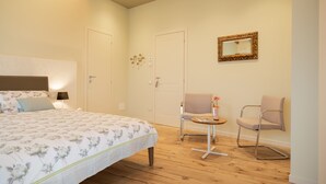 A bedroom with a bed, two chairs, a small table, and a mirror on the wall. - Casa Pralunghi b&b  (Calvene)