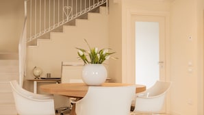 A dining area with a wooden table, white chairs, and a potted plant. - Casa Pralunghi b&b  (Calvene)