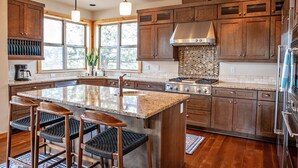 Une cuisine spacieuse dotée d’un grand îlot central, de meubles en bois et d’une cuisinière moderne.