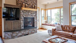 Una sala de estar con chimenea de piedra, televisor y sofá de cuero.