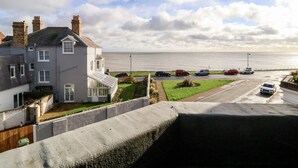 A residential area with a view of the sea, a parking lot with several cars, and a large house with multiple chimneys. - Collett House (Reydon)