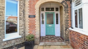 A brick building with a teal door, a sign reading "Collett House," and a small potted plant by the entrance. - Collett House (Reydon)