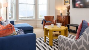 A living room with a sofa, armchair, coffee table, and a flat-screen TV. - Collett House (Reydon)