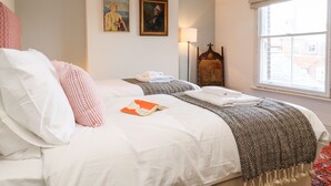 A hotel room with a large bed, a window with a view, a lamp, and two framed pictures on the wall. - Collett House (Reydon)