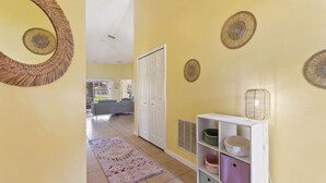 A hallway with a patterned rug, a white door, and a shelf with baskets. - Gilded Parasol By Shine Villas Remington Golf #410 4 Bedroom Home (Kissimmee)