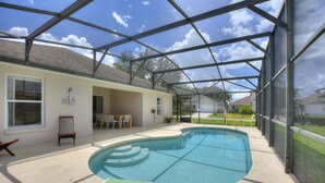 A covered swimming pool with a green deck, a chair, and a table. - Gilded Parasol By Shine Villas Remington Golf #410 4 Bedroom Home (Kissimmee)