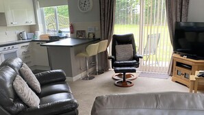Ein modernes Wohnzimmer mit einer Ledersofa, einem schwarzen Relaxsessel und einem Fernsehschrank.