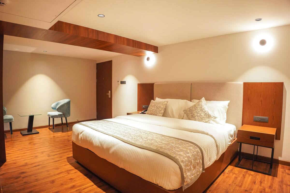 Una habitación de hotel moderna con una cama grande, una mesita de noche, una silla y una pequeña mesa.
