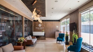 A modern reception area with a sofa, blue armchairs, and a TV. - Ramee International Surat (Surat)
