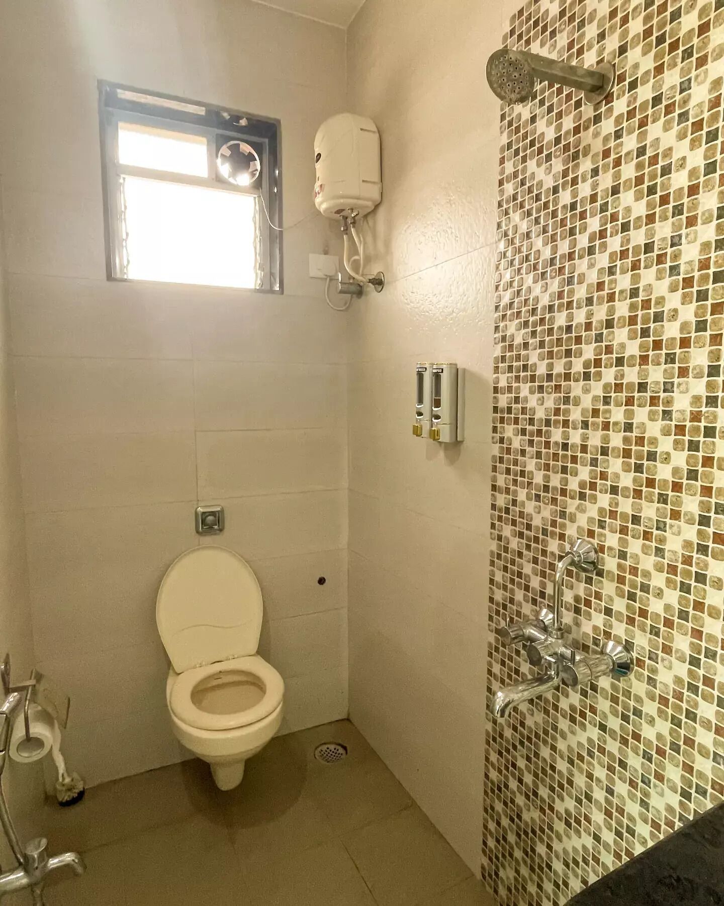A small bathroom with a toilet, a shower, and a window.