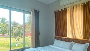 Ein Hotelzimmer mit einem großen Bett, einem Fenster mit Vorhängen und einer Klimaanlage an der Wand.
