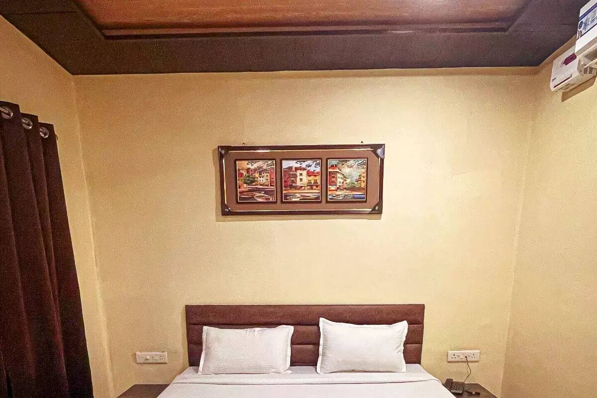 A double bed with white linens, two pillows, and two folded towels on a wooden frame.