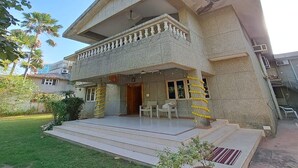 A two-story building with a balcony, a front porch, and a small garden area. - Elis Hospitality Service Parth Bungalow (Ahmedabad)
