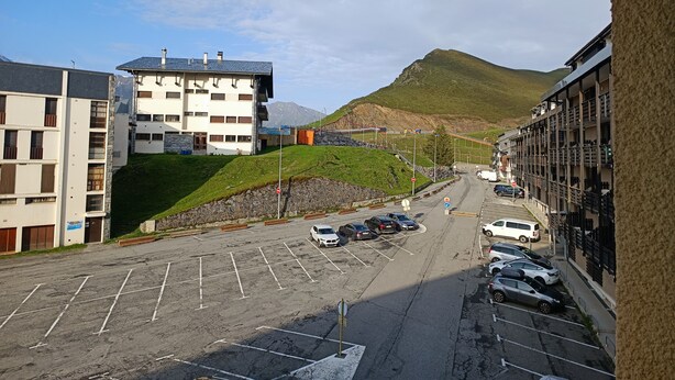 Ein Parkplatz mit mehreren Autos, ein mehrstöckiges Gebäude und ein Berg im Hintergrund.