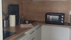 Eine kleine Küche mit Mikrowelle, Spüle und Mülleimer.