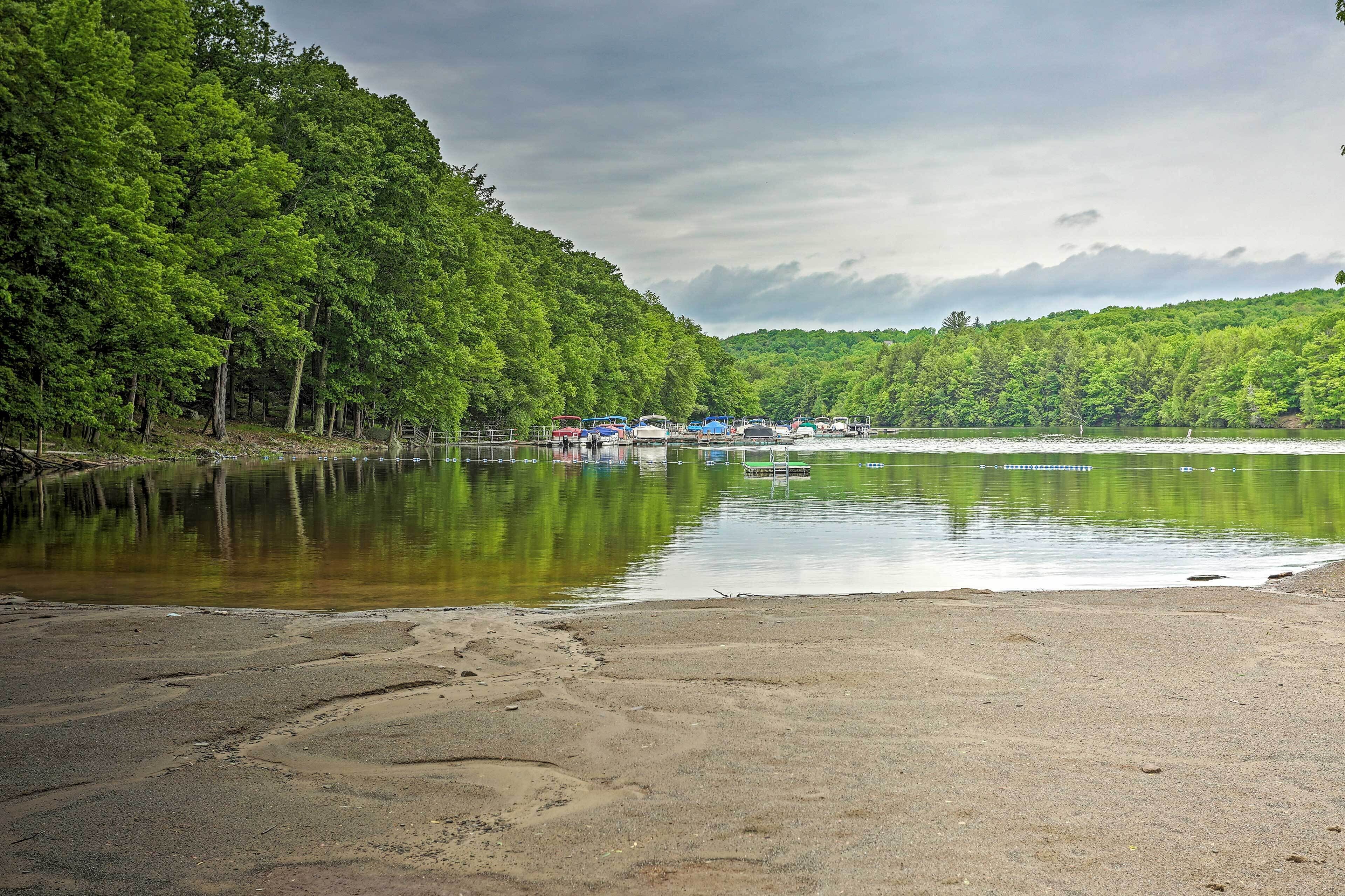 Une zone au bord du lac, avec une plage de sable et une rangée de bateaux amarrés le long de la rive.