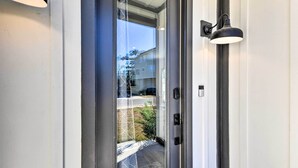 A modern door with a glass panel, a keypad lock, and a wall-mounted light fixture. - Spacious Gulfport Home - Walk to Beach! (Gulfport)
