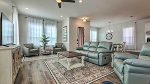 A modern living room with a sofa, armchairs, a coffee table, and a TV. - Spacious Gulfport Home - Walk to Beach! (Gulfport)